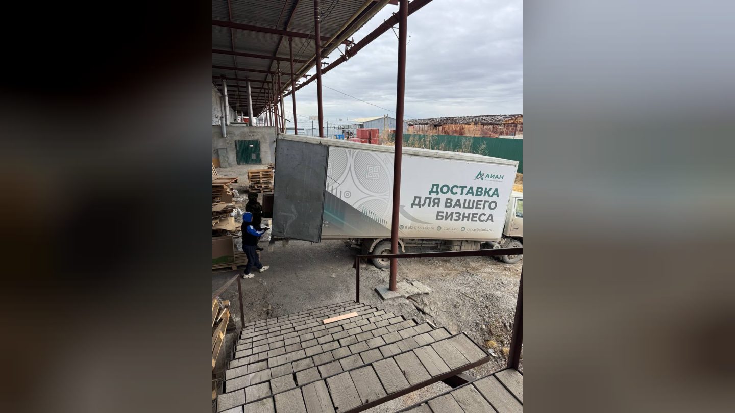 Машина доставки ТК АЙАН у склада, грузчики переносят отправления из фуры
