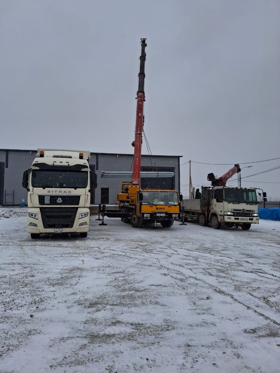 Выгрузка первой фуры на площадке нового склада: автокран и манипулятор