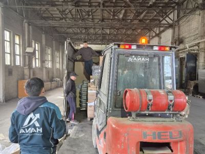Разгрузка сборной фуры вилочным погрузчиком на складе АЙАН в Якутске, сотрудники принимают коробки