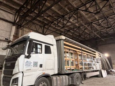 Шторный полуприцеп с открытой боковиной внутри склада, груз в деревянных обрешетках